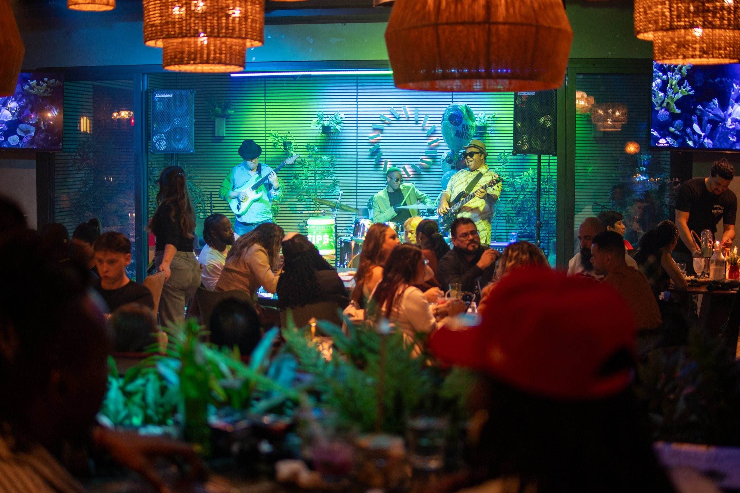 A live band on stage and a full lounge under the woven pendant lamps at Sessions By The Bay